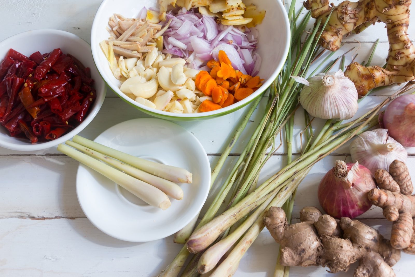 Cut garlic, onion, ginger, dried chillies and turmeric laid out on a white table