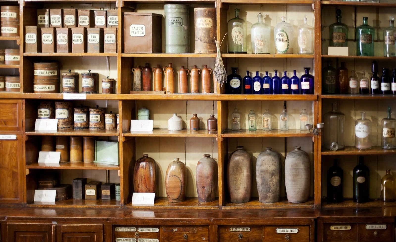 A wall of small wooden drawers holding an assortment of herbs and spices