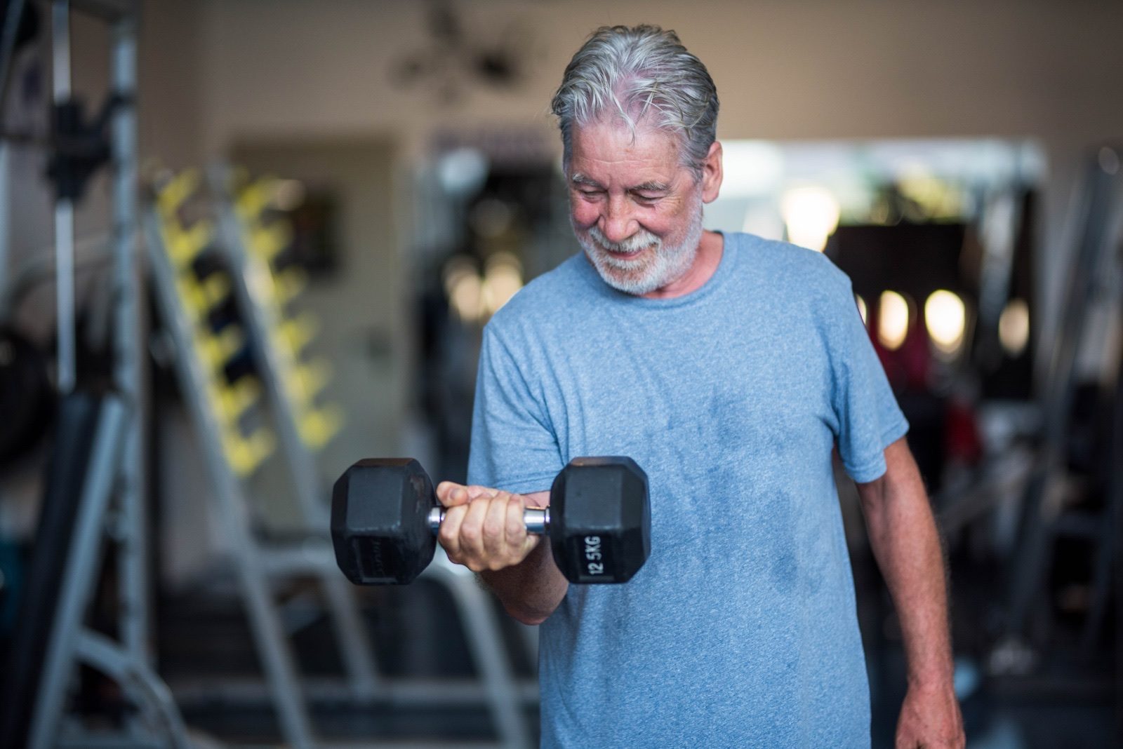 A man in his fifties lifting a dumbbell in a gym