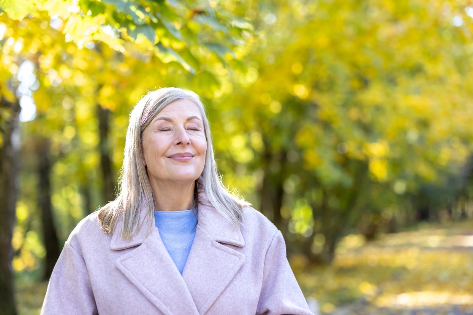 A woman outdoors enjoying autumn sunshine