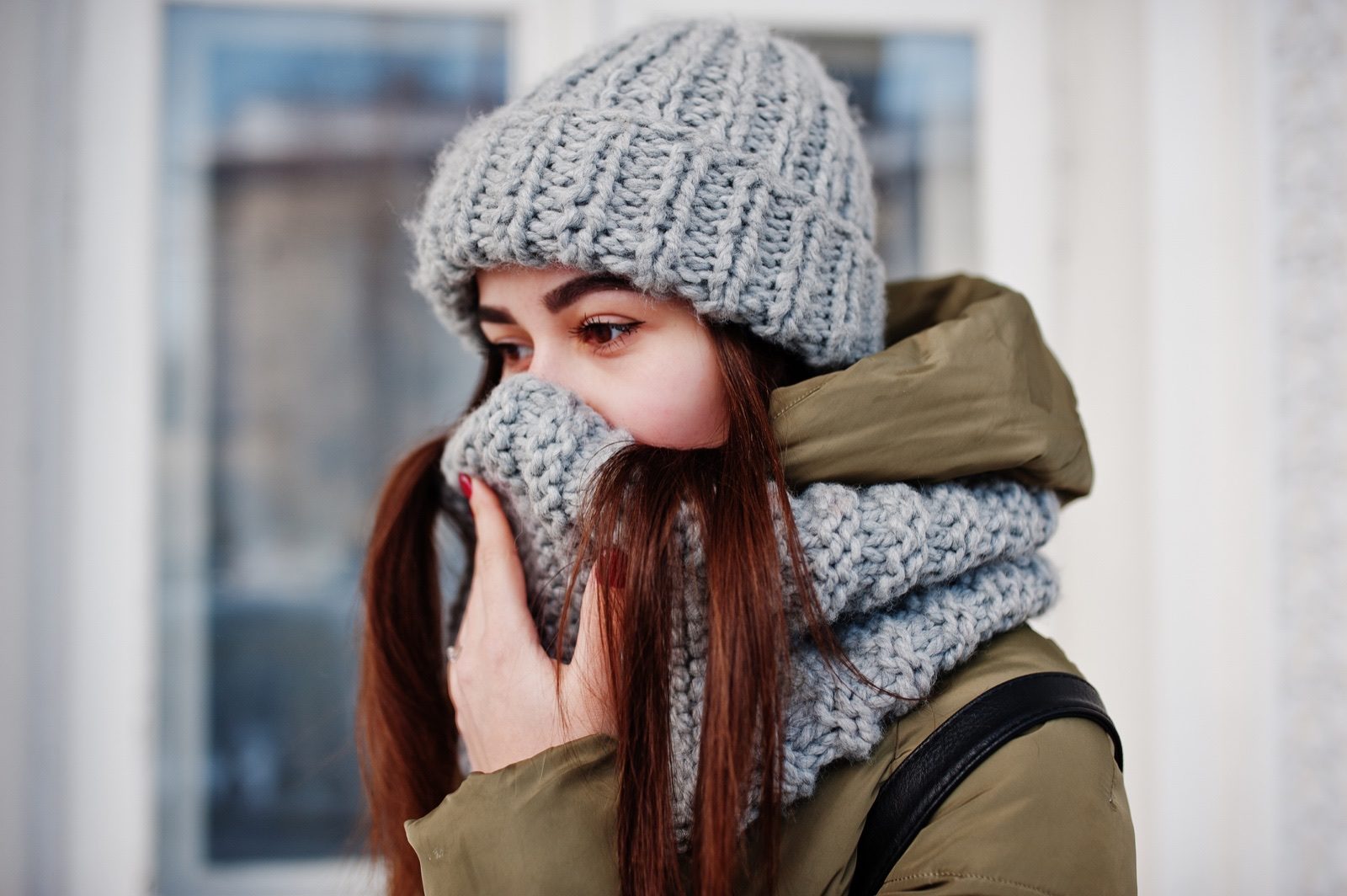 A woman outdoors in cold weather wearing a scarf and hat