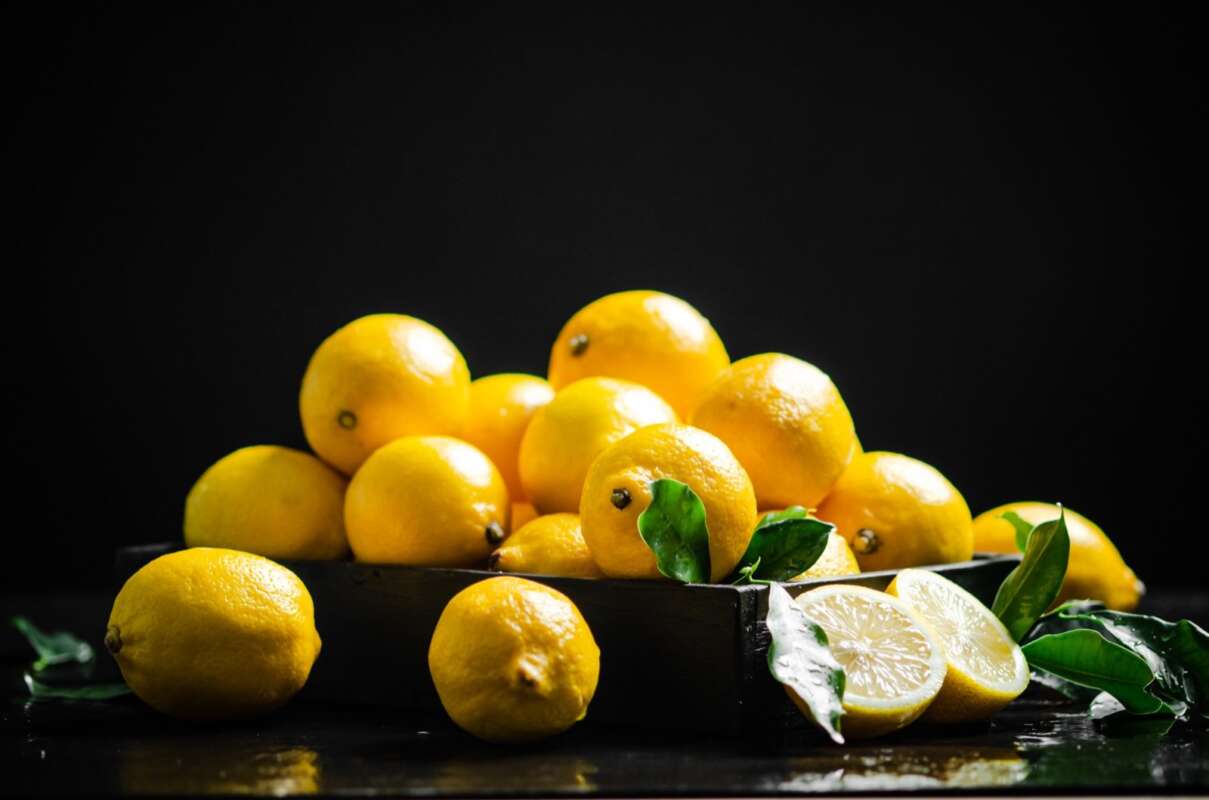 Whole lemons and leaves in a wooden crate
